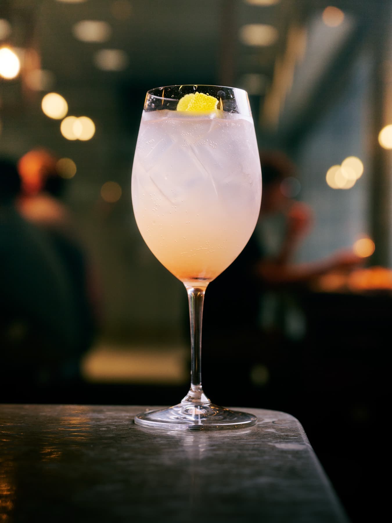 A blush-pink spritz against warm bar lights